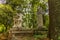 A path in a garden in Rome with old statues, columns, and water fountains