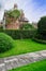 Path in grassy lawn before hedged houses on sunny autumn day