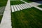 Path through the grassy meadow of the garden. tiles with stripes tile pattern. concrete white lawn diagonally. garden details with