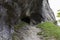 Path leading to entrance to the cave in Jura mountains. Black hollow in rock. Mountain tunnel hiking trail, cave enter of dark