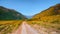 Path through mountains. Trekking mountain trail. Bright panoramic alpine landscape with dirt road among grasses in highlands.