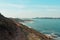 Path near the cliffs in the north of spain with massive waves and a white lighthouse in the end