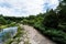 Path near stones, pond and green trees with fresh leaves