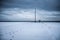 Path to enlightenment. Snow covered beach with footprints leading to antique lamp post.