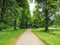 Path through trees and green grass verges in a country estate in England