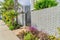 Pathway along wrought iron gate and brick fence at the entrance of modern home