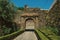 Pathway going toward gateway in stone wall with garden