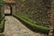 Pathway going toward gateway in stone wall with garden