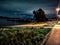 Pathway at night at the riverside of the river Rhein in Cologne with sand beach and moody autum sky