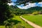 Pathway passes through lush grassy fields amidst a beautiful tranquil nature with the mountains in background. Beautiful view of