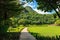 Pathway passes through lush grassy fields amidst a beautiful tranquil nature with the mountains in background. Beautiful view of