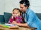 Patience mum with daughter unable to concentrate whilst doing homework sitting on sofa at home in learning difficulties homework