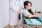 Patient asian woman paralysis is sitting in a wheelchair with doctor standing behind haul to her,Healthcare concept