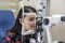 Patient on diagnostic of vision, oculist cabinet. Optician measuring a woman`s eyesight. Young woman visiting ophthalmologist in