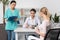 Patient with doctor and internist sitting at table during consultation in clinic