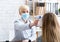 Patient examination. Woman doctor in protective mask measures temperature