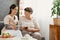 Patient of nursing home and her helpful volunteer sitting on couch and drinking herbal tea together