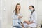 Patient with test tube with blood posing in hospital. Doctor with clipboard and patient sitting on sofa