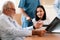 Patient in wheelchair discuss her health with doctor in sterile room.