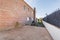 Patio of a detached house with light brown stoneware floors, exposed brick walls, lawned gardens and swings for children