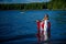 Patriot woman standing in the mazarine color water of the Cultus Lake and holding up a Canadian flag