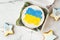 Patriotic cake decorated with yellow and blue Ukrainian flag. Small trendy bento cake in the white gift box. Korean style little