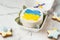 Patriotic cake decorated with yellow and blue Ukrainian flag. Small trendy bento cake in the white gift box. Korean style little