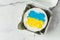 Patriotic cake decorated with yellow and blue Ukrainian flag. Small trendy bento cake in the white gift box. Korean style little