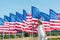 Patriotic child standing in white dress near american flags and waving hand