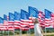 Patriotic child standing in white dress near american flags and waving hand