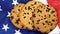 Patriotic cookies. Three rounded traditional chocolate chip cookies on the background of the flag of the United States of America