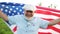 Patriotic day. An elderly man with the American flag on a background of green grass. US Independence Day Celebration