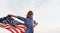 Patriotic female kid with American Flag in hands. Against cloudy sky