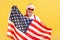 Patriotic happy gray bearded man in stylish sunglasses and santa claus hat holding flag of united states of America, voting on