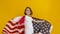 Patriotic holiday. Happy child, cute girl with American flag on yellow studio background. USA celebrate July 4th