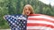 Patriotic holiday. Happy emotional woman with American flag on green forest background during summer day outdoors. USA