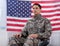Patriotic soldier sitting on wheel chair against american flag