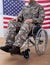 Patriotic Soldier Sitting On Wheel Chair Against American Flag