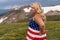 Patriotic young woman wearing an American Flag dress looks concerned at Beartooth Highway in Wyoming