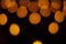 Pattern of blurred warm lights on black background. Rounded lights of warm colors