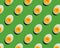 pattern of boiled eggs cut in half on green background.