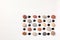 Pattern of colored pebbles and black glass beads on white wooden background. Flat lay, top view
