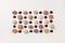 Pattern of colored pebbles and black glass beads on white wooden background. Flat lay, top view