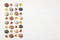 Pattern of colored pebbles and orange glass beads on white wooden background. Flat lay, top view