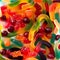Pattern of colorful gummy bears and worms against white background top view.