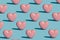 Pattern created of artisan french patisserie concept. Pink heart shaped yummy irresistible macaron alone against baby blue