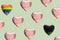 Pattern created of many pink heart shaped balloons, a rainbow color and a black balloon. Green pastel background. Diversity, LGBT