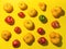 Pattern of farm tomatoes of different colors and sizes with hard shadows on bright yellow background