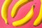 Pattern from floating flying in the air yellow bananas on fuchsia pink background. Tropical fruits vitamins healthy vegan diet