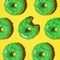 Pattern of green donuts on a yellow background. Square, studio photo